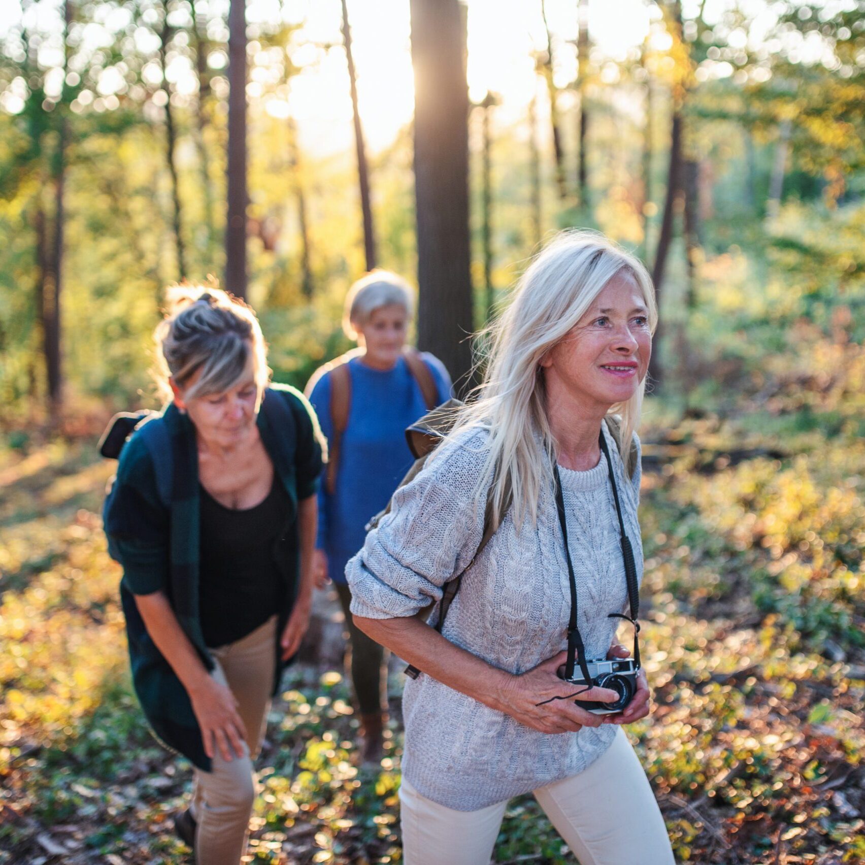 Senior women friends on a walk outdoors in forest, walking.